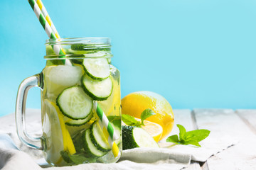 Summer fresh water detox with lemon, cucumber, ice and mint in mason jar on a white wooden background. Rustic style.
