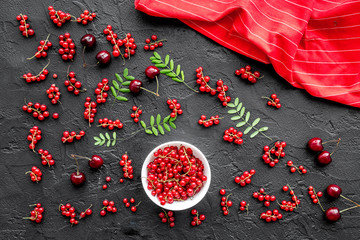 Berry theme. Red currant, cherry and leaves on black table background top view mockup