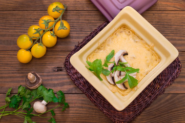 Hot Julienne with juicy chicken, mushrooms, cream sauce and cheese. Meat appetizer. Wooden background. Top view. Close-up