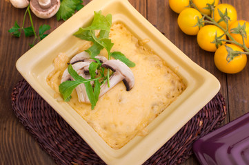 Hot Julienne with juicy chicken, mushrooms, cream sauce and cheese. Meat appetizer. Wooden background. Top view. Close-up