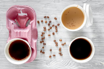 Coffee to go. Coffee cups with cover and coffee beans on wooden table backound top view