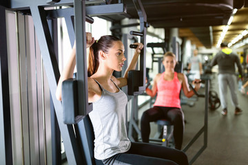 Fototapeta na wymiar Young women exercising on machine in gym