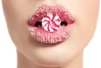 Beautiful young woman holding candy in lips covered with sugar, closeup