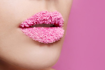 Lips of beautiful young woman covered with sugar on color background