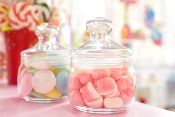 Tasty sweets in jars on table at candy shop