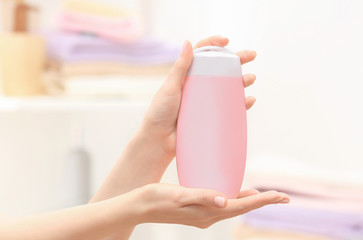 Hands of woman with bottle of cosmetic product in bathroom