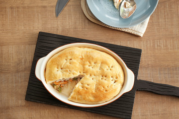 Baking dish with turkey pot pie on wooden table