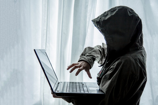 Hacker or terrorists  in hood with masked working on dark digital his on computer. Hacking the system cyber crime concept .