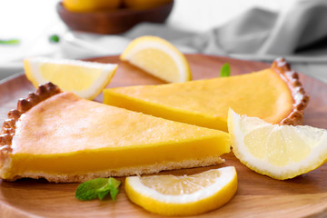Wooden plate with delicious lemon pie on table, closeup
