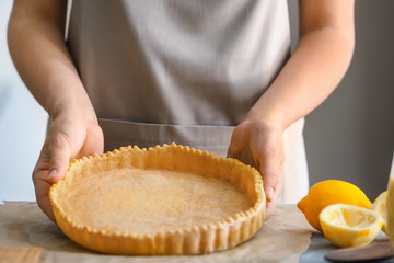 Obraz na płótnie Canvas Woman cooking lemon pie in kitchen, closeup