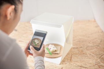 Young women taking photo to roll cake with cell telephone or smartphone digital camera for Post to show and sell Online on the Internet . for selling online business internet of things concept