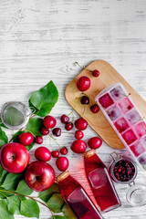 Summer ice tea with apple, cranberry and pulm on wooden table top view copyspace