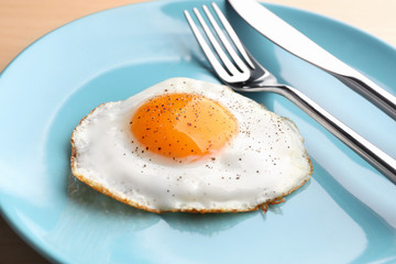 Plate with sunny side up fried egg on table