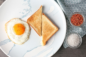 Composition with sunny side up fried egg with toasts and spices on grey table