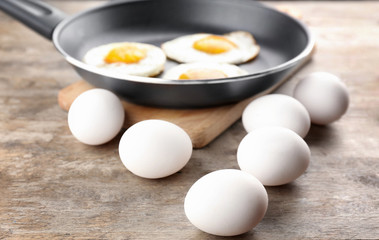 Composition with raw and sunny side up fried eggs on wooden table