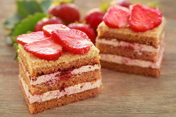 Two pieces of homemade cake with strawberries on wooden table