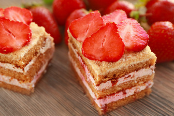 Two pieces of homemade cake with strawberries on wooden table