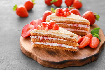 Two pieces of homemade cake with strawberries on wooden board