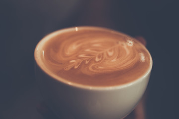 A cup of coffee with fern pattern in a white cup hand holding, vintage color ,Thailand