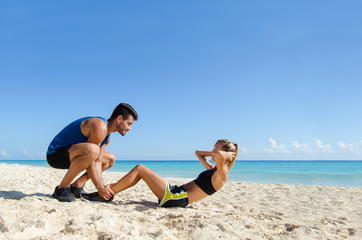 Couple training abs at the beach