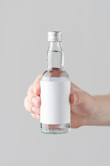 Miniature Spirits / Liquor Bottle Mock-Up. Blank Label - Male hands holding a liquor bottle on a...