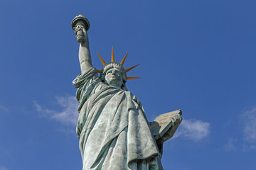 Statue of Liberty on the island Cygnes in Paris against blue sky