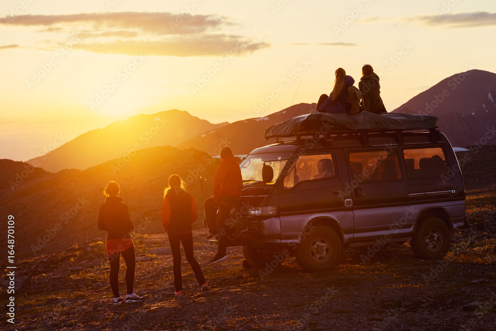 Wall mural Travel concept with friends, sunset and car