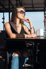 Beautiful blond girl sits at a table in a cafe on the street