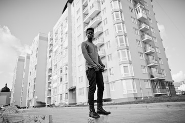 Handsome and attractive african american man posing next to the tall building on a street.