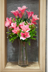 Beautiful flowers in a glass vase on wall backgroundwith wooden frame