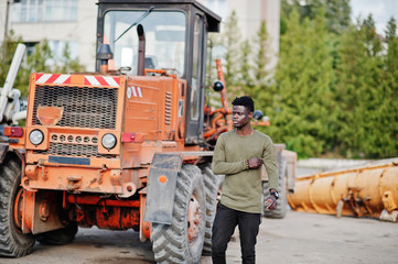 Portrait of an attractive black african american man posing next to the industrial machinery.