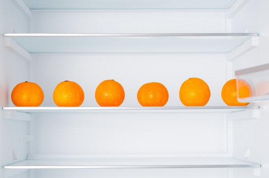 Empty fridge and ripe tangerines on shelves
