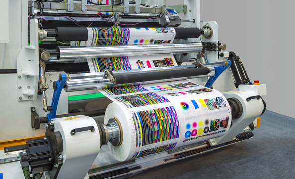 Large offset printing press or magazine running a long roll off paper in production line of industrial printer machine.