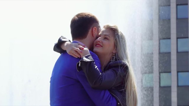 Lovely couple embrace against the background of the fountain in the downtown. Beautiful couple spend time together