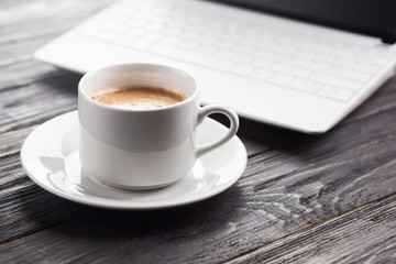 Laptop and coffee cup on wooden table