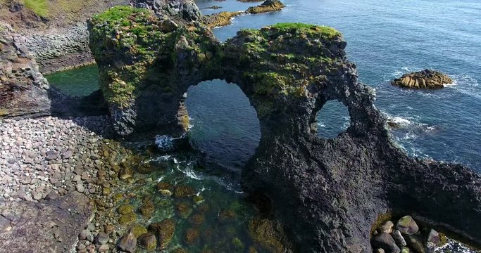 Rotating Aerial Of Rocky Sea Arches On The Beach With Birds Flying - Hellnar Arches in Iceland