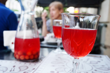 Glass of red Cherry juice in outdoor cafe blurry background