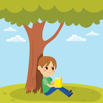 Young little kid reading a book sitting under tree