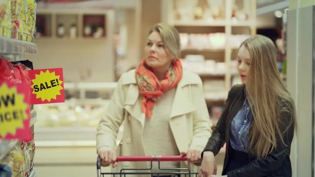 Sale at the grocery store. Woman with daughter chooses products discounts