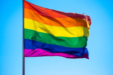 Rainbow flag waiving in the wind with sun shining through it