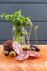 Appetizer of salami, green and calamata olives and arugula served on hymalayan pink salt block