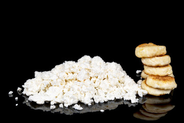 Heap of cottage cheese and cheese cakes made out of it isolated on a black background