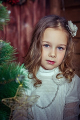 Child girl in a Christmas interior. A Christmas card. Near the Christmas tree with a star.