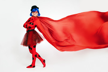 The girl with a red cape. Woman comic book character. Cosplay girl. Red cape develops in the air. - obrazy, fototapety, plakaty