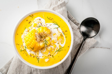Vegan cuisine. Traditional autumn corn soup. Served with corn cobs, greens, cream. On a white...