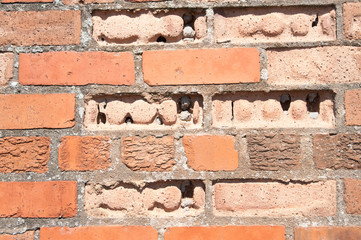 Severely weathered and eroded bricks in a wall.
