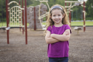 young girls at the playground smiling with her arms crossed