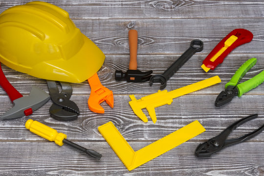 Colored toy tools and a builder's helmet, scattered on the table. The idea: building construction, engineer, architect, repair, mantage.