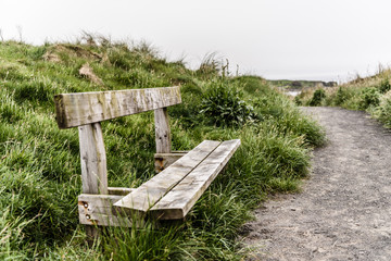 An empty wooden bench on a coastal path.