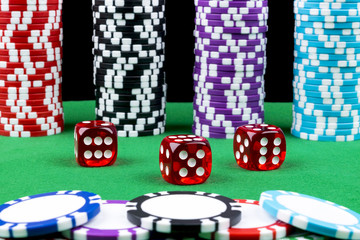 Stack of Poker chips on a green gaming poker table with poker dice at the casino. Playing a game with dice. Casino dice Concept for business risk, chance good luck or gambling. Poker chips and dice 